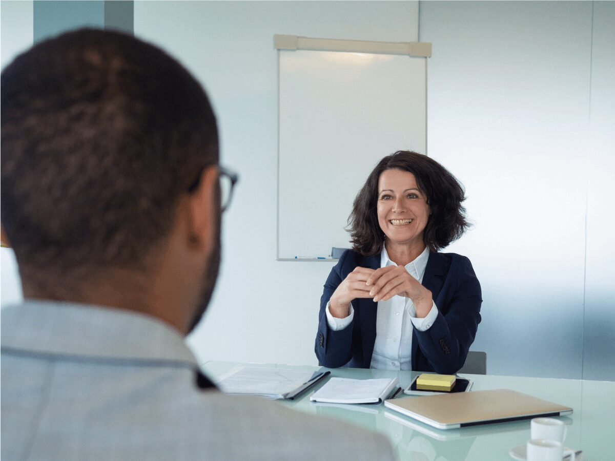 Trainerin im Gespräch mit Teilnehmer am Tisch im Seminar Nein sagen lernen
