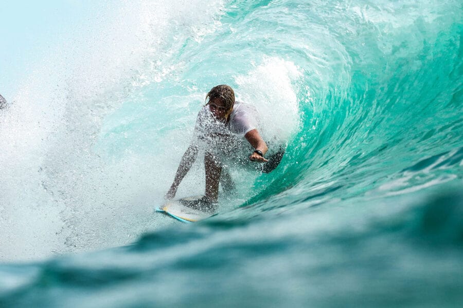 Surfer auf Welle im türkisfarbenen Meer, dynamische Actionaufnahme