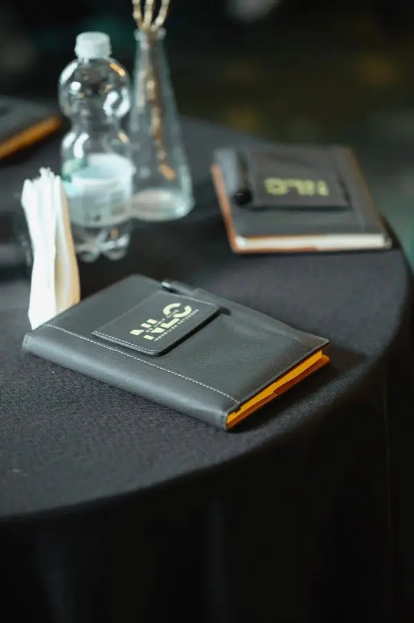 Nahaufnahme schwarzes NLC-Notizbuch und Wasserflasche auf Event-Tisch