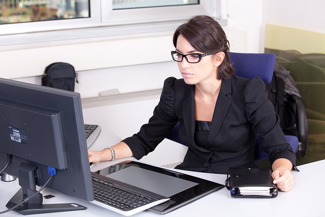 Frau am Schreibtisch mit Laptop und Tablet bei der Online-Arbeit