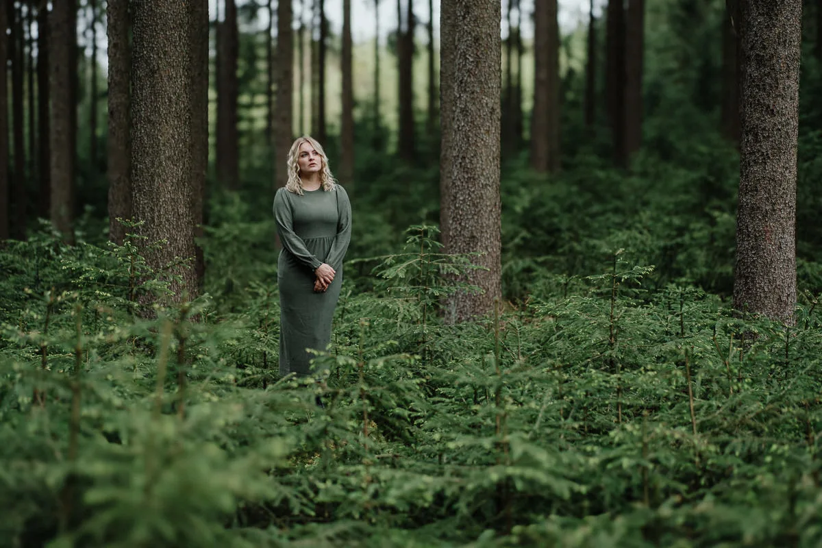 Frau in grauem Kleid im Wald mit bearbeiteten Bokeh-Effekten, helles Ergebnis