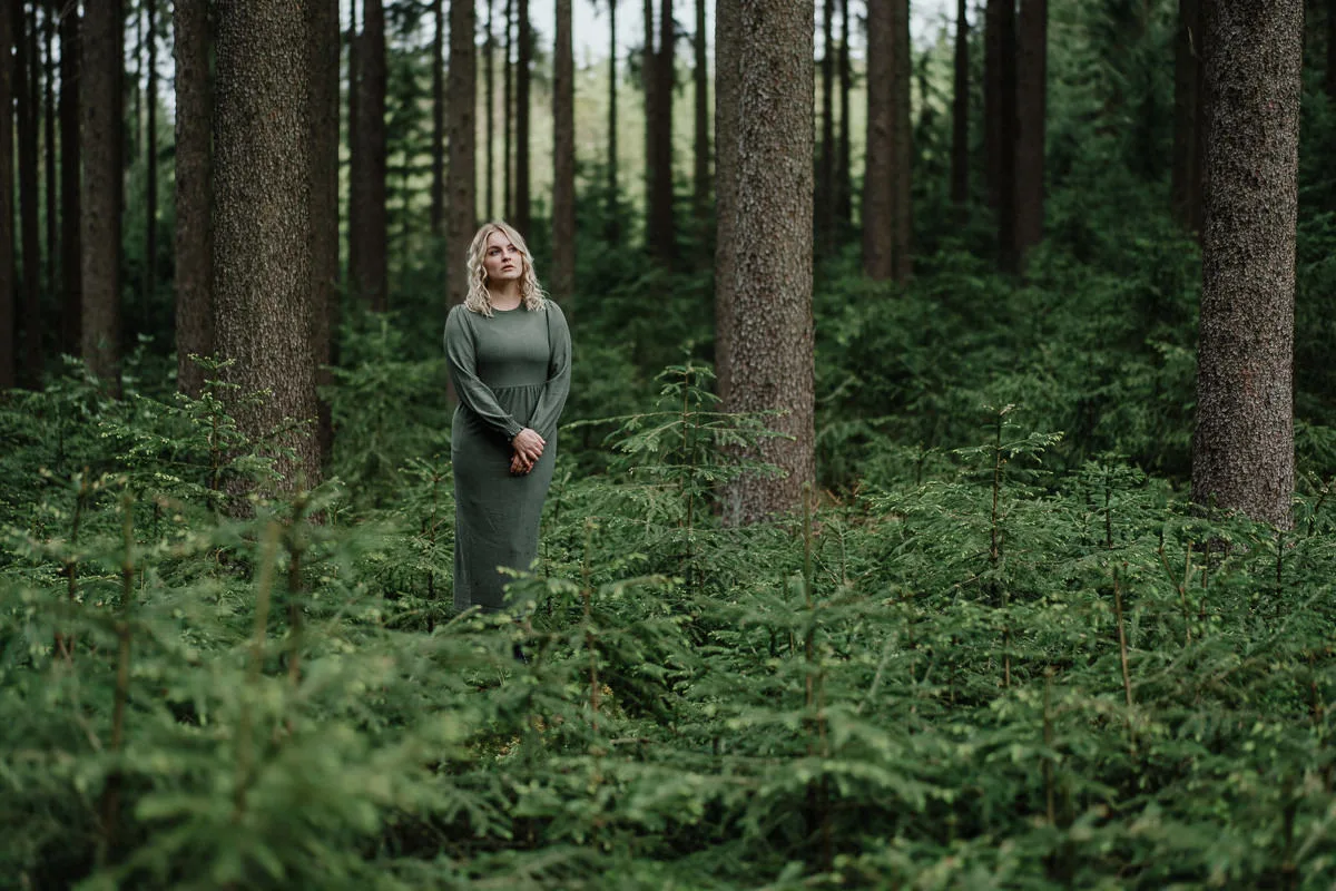 Frau in grauem Kleid im Wald mit vintage Bokeh-Effekten, wärmere Farbgebung