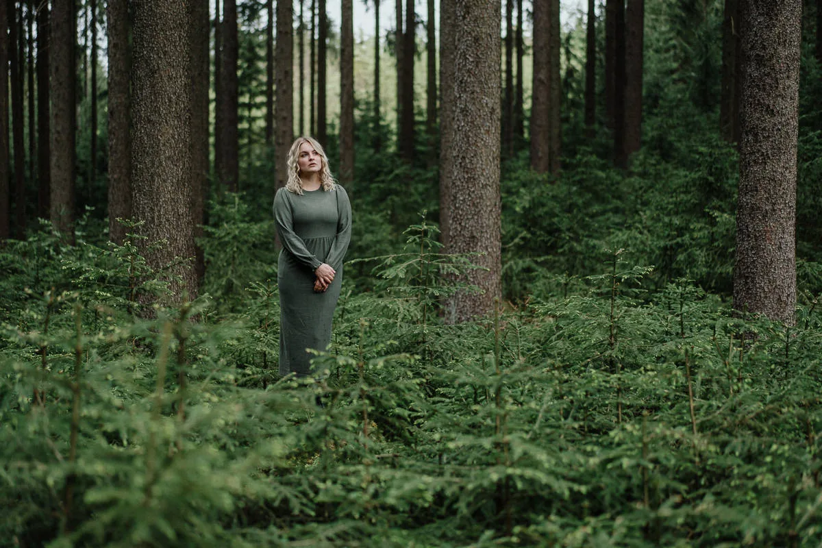 Frau in grauem Kleid im Wald zwischen Bäumen, vorher-Aufnahme ohne KI-Effekte