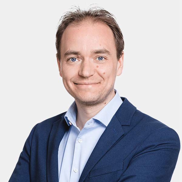 Mann mit braunem Haar in dunkelblauem Blazer und hellblauem Hemd