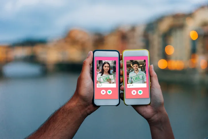 Zwei Hände halten Smartphones mit Dating-App-Interface nebeneinander