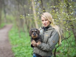 Frau Conny Sporrer hält kleinen braunen und schwarzen Hund im Wald