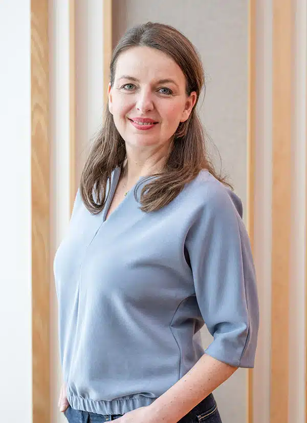 Jana, Frau mit braunem Haar, blaues Oberteil, Hochformat-Porträt