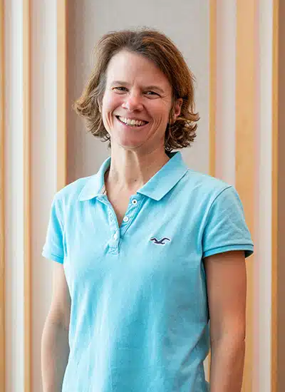 Stephanie Souron, Frau mit lockigem Haar, türkises Polo-Shirt