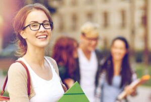Junge Frau mit Brille auf Campus mit Studienmaterialien