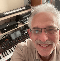 Erhard Earnie Schrebb, älterer Mann mit weißen Haaren und Brille vor Keyboards