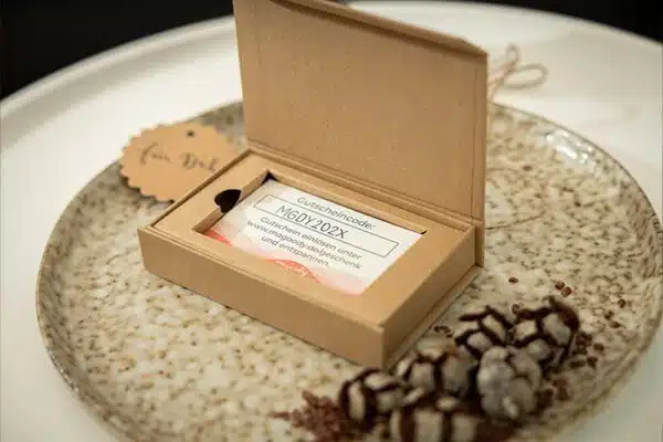 Magoody Geschenkbox mit Gutschein auf dekorativer Steinplatte mit Kerze und Blume