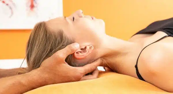 Entspanntes Frau bei Paarmassage-Behandlung mit Kopfmassage vor gelbem Hintergrund