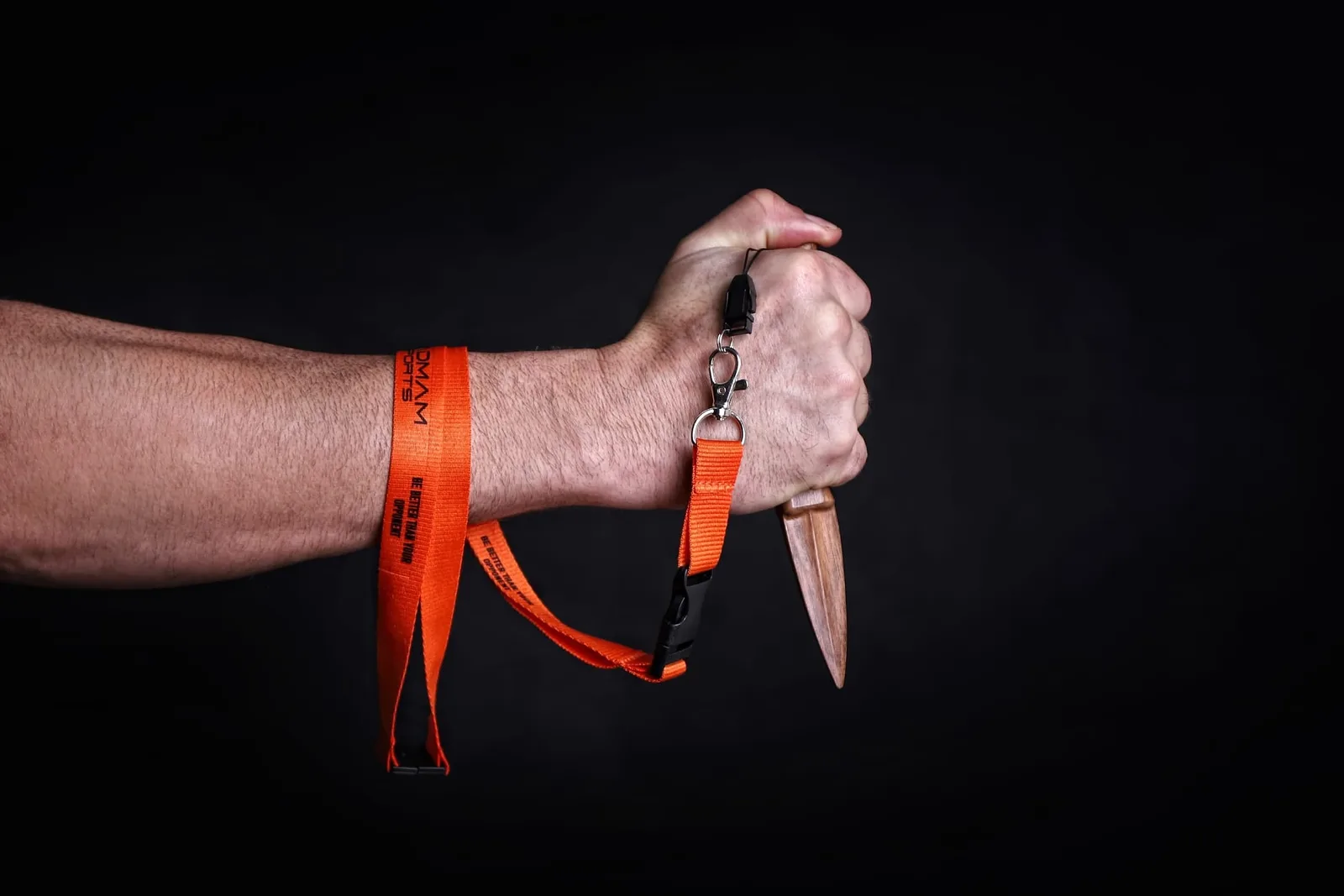 Holz-Spike mit rotem PADMAM-Schlüsselband in Hand demonstriert