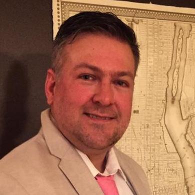 Porträt Mann in Blazer mit rosa Krawatte vor Wandkarte