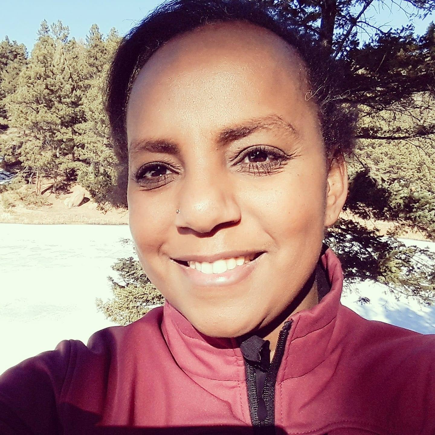 Frau in Burgundy-Jacke vor Nadelwald und Schnee