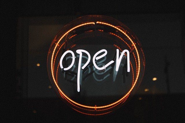 Neon-Schriftzug 'open' in orange-weißem Licht vor dunklem Hintergrund