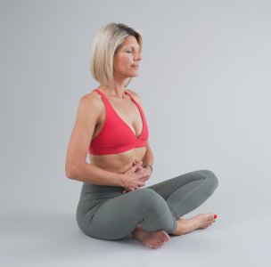 Frau in rosa Sportbra und grauer Leggings sitzend mit Nachdenklicher Pose