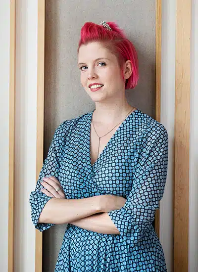 Tamara Krantz mit pink gefärbtem Haar, blauem Muster-Shirt, Arme verschränkt
