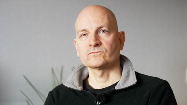 Christoph G., Privatier, Portrait mit grauem Hintergrund und Hoodie