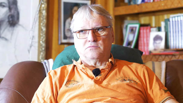 Karl-Heinz G., LKW-Fahrer i.R., mit Brille in orangefarbenem Shirt