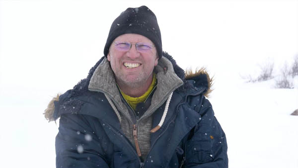 Achim K., Abenteurer, lächelnd mit Wintermütze und Brille im Schnee