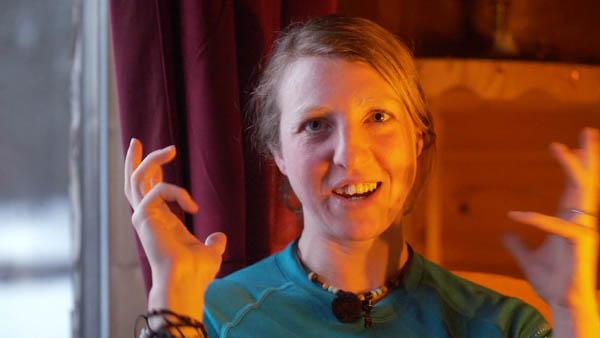 Meike S., Sozialarbeiterin, lächelnd in blauem Shirt vor warmem Licht, gestikulierend