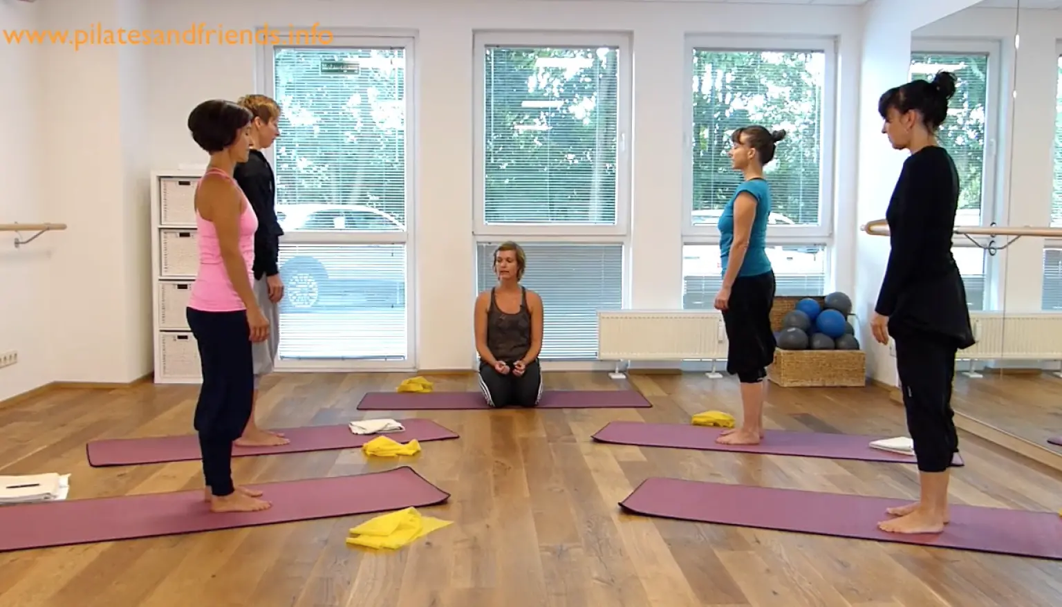 Pilates-Kursstunde mit mehreren Teilnehmern auf Matten im hellen Studio