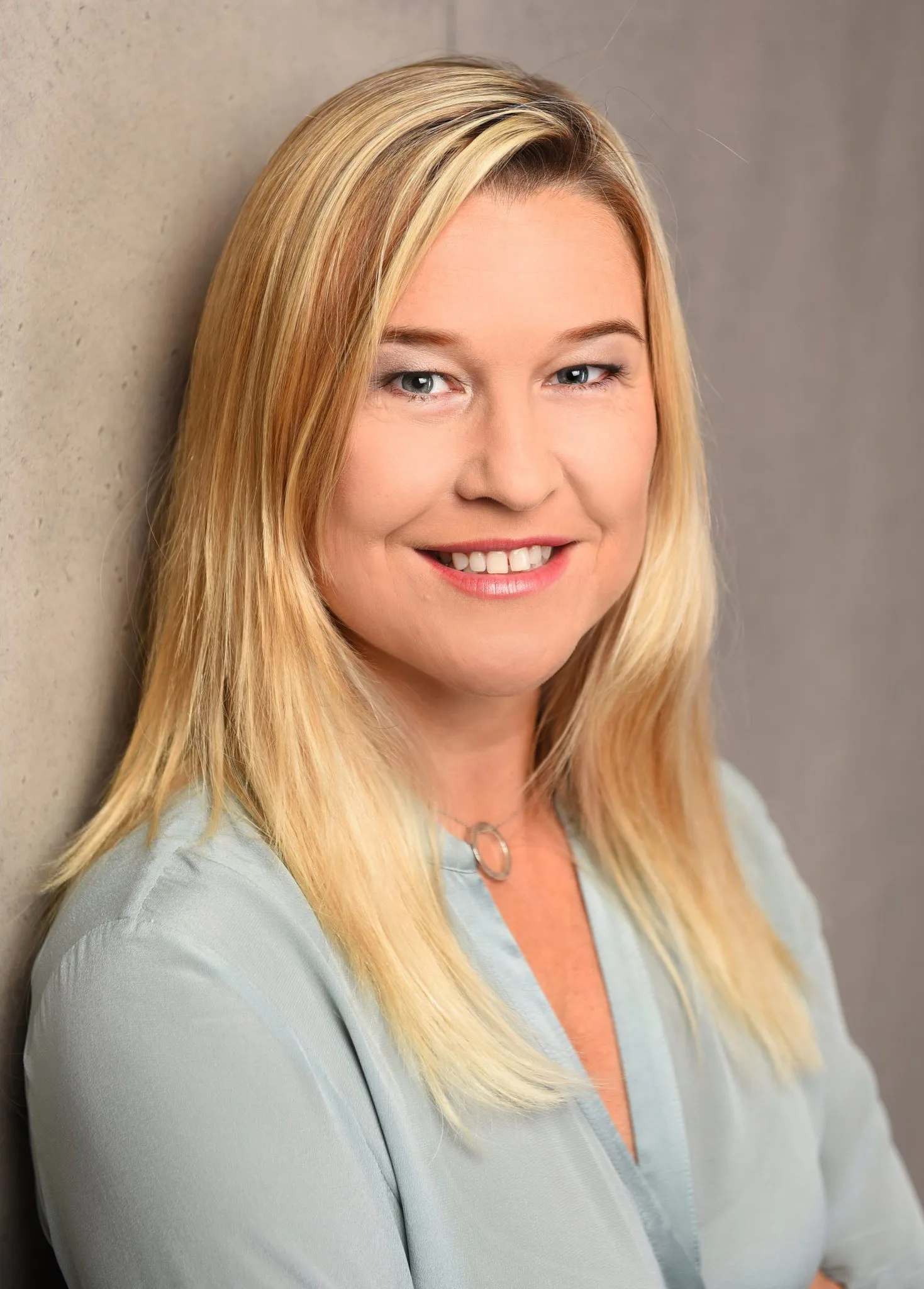 Porträtfoto Michaela Peschmann, Heilpraktikerin Psychotherapie München mit blondem Haar, hellblauem Blazer und korallenfarben