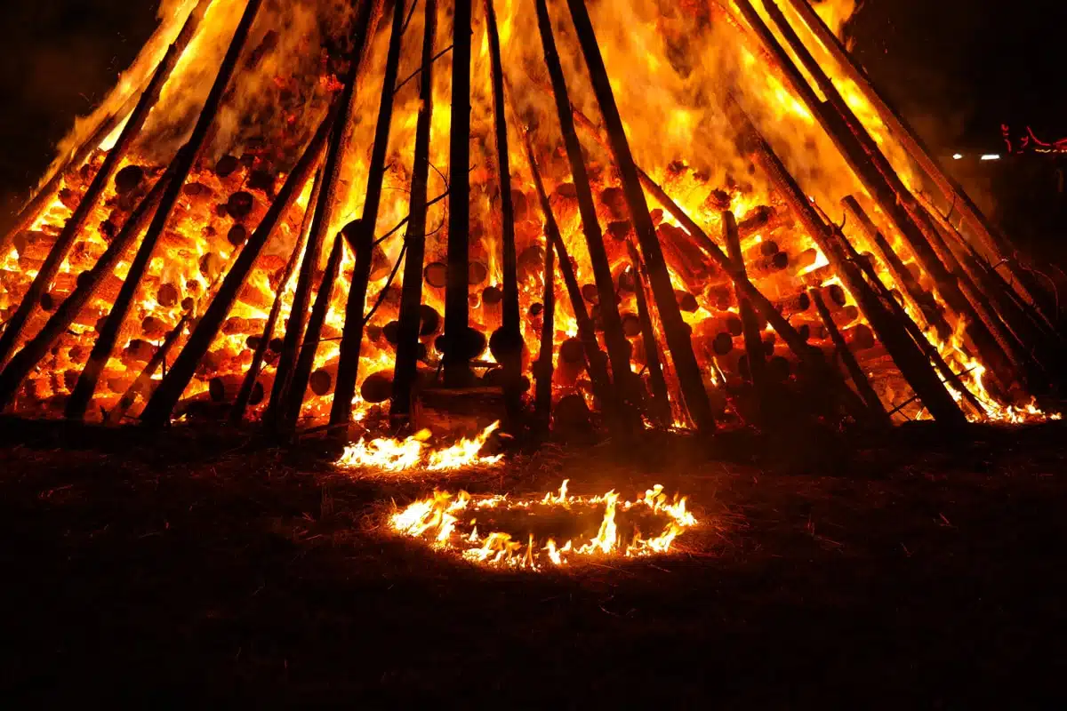 Großes brennendes Lagerfeuer mit Holzgerüst in der Nacht, Litha Sommersonnenwende