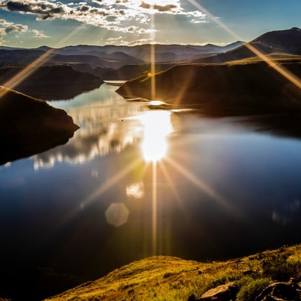 Berglandschaft mit Fluss und Sonnenlicht über Wasser