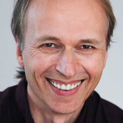 Porträt Stephan Petrowitsch, Mann mit Geheimratsecken und freundlichem Lächeln in schwarzem Shirt