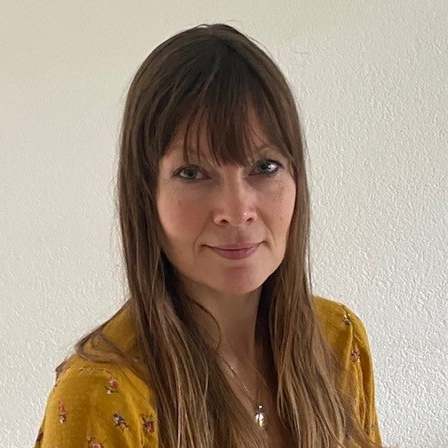 Porträt Dana Dreier, Frau mit dunklen Haaren und gelbem Pullover vor weißem Hintergrund