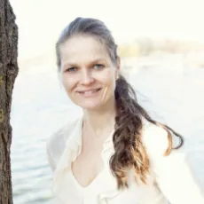 Porträt Salomea Klaus, Frau mit braunen geflochtenen Haaren in weißem Oberteil am Wasser