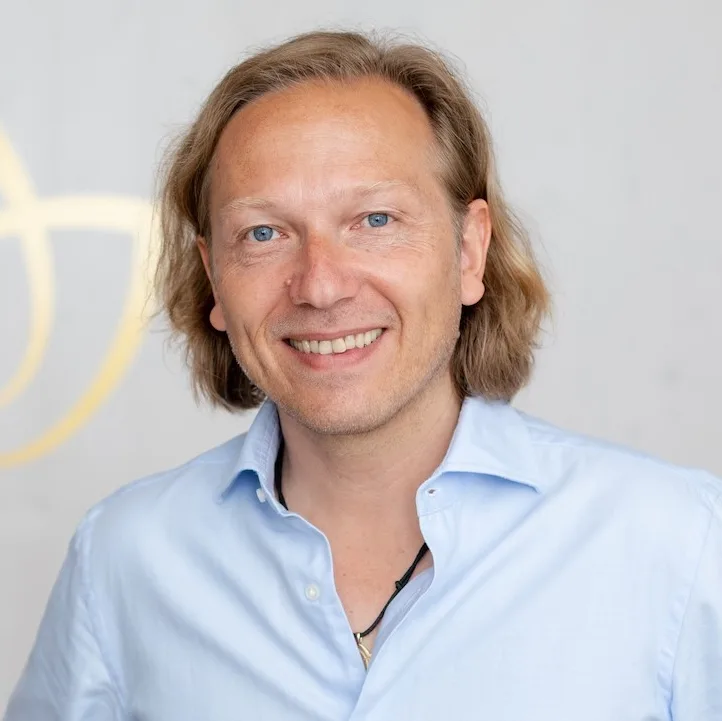 Porträt Nikolaus Lackner, Mann mit blonden Haaren in hellblauem Shirt vor weißem Hintergrund