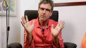Mike Hellwig in rotem Hemd im Studio bei Interview, gestikulierend