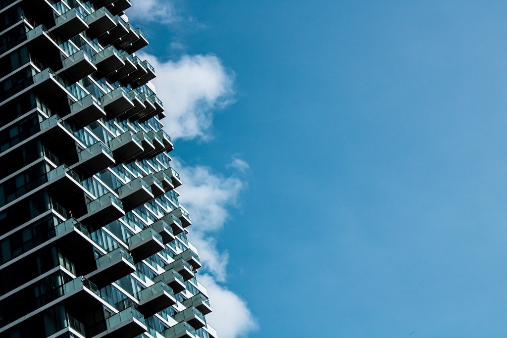 Modernes Hochhaus mit Balkonen vor blauem Himmel mit weißen Wolken
