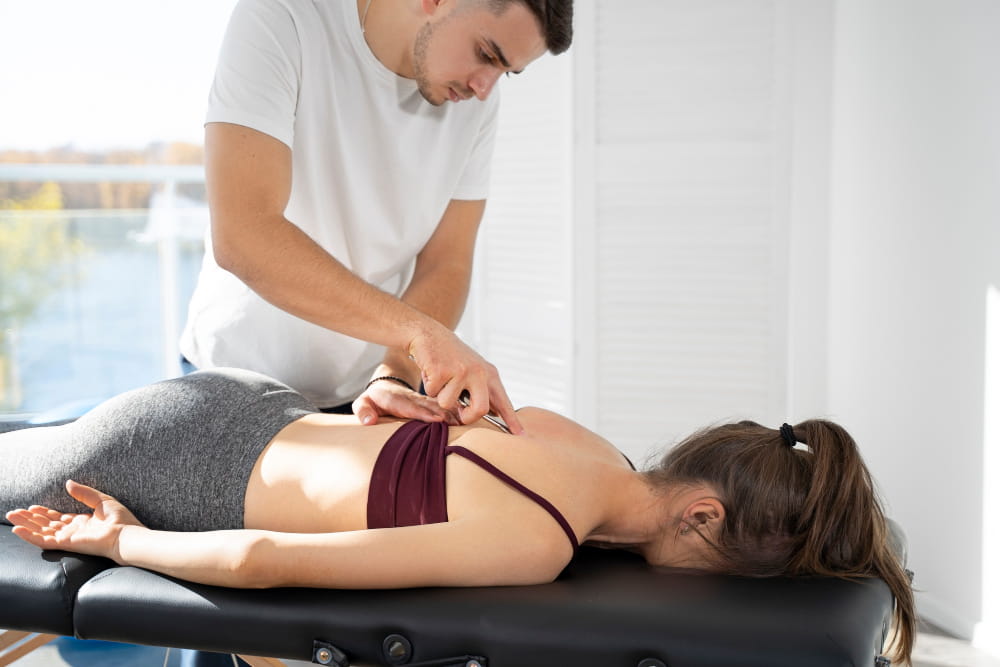 Therapeut behandelt Rücken einer Frau auf Massageliege mit professioneller Technik