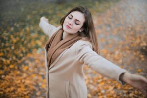 Frau mit ausgebreiteten Armen breitet sich entspannt aus, herbstliche Kulisse