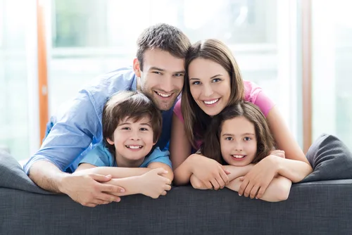 ReConnect Factor 2.0 – E-Book zum Ex-Zurückgewinnen von Marko Slusarek 5 Glückliche vierköpfige Familie auf Sofa, Eltern mit zwei Kindern lachend