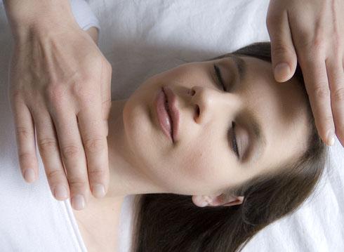 Therapeutische Hände bei Reiki-Behandlung auf Kopf einer entspannten Person