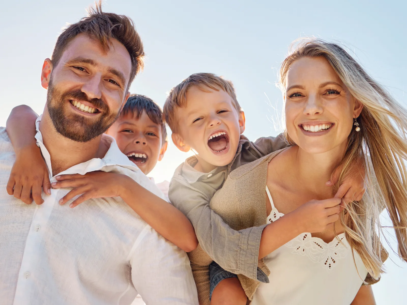 Glückliche Familie mit zwei Kindern am Strand bei Sonnenuntergang lachend