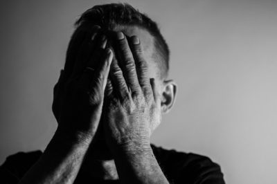 Mann mit Hand vor Gesicht zeigt Stress und Angst, Schwarz-Weiß-Fotografie