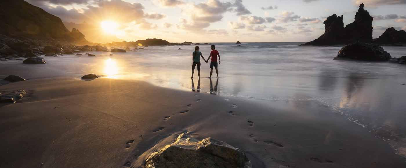 Zwei Personen im Meer an Strand mit Felsen und Sonnenuntergang, Reiseblog Phototravellers