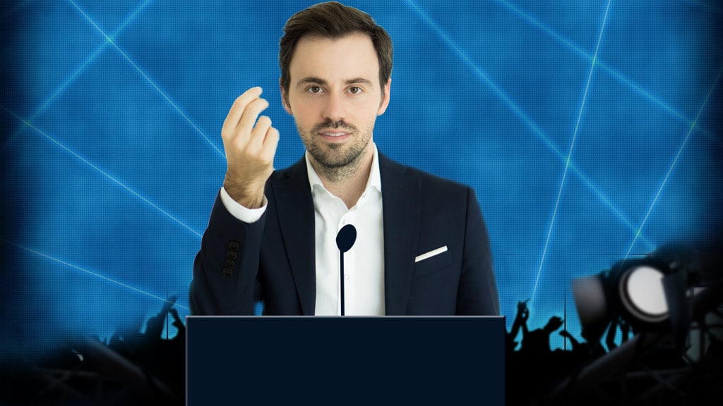 Mann im dunklen Anzug und weißem Hemd gestikuliert vor blauem technologischem Hintergrund mit Publikum