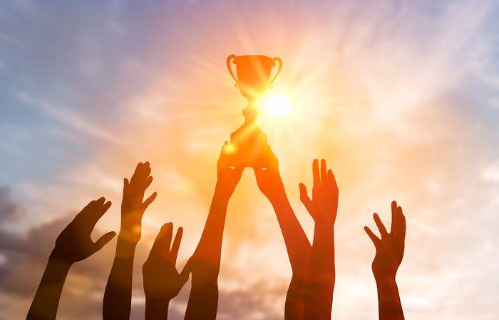 Hände halten goldenen Pokal vor Sonnenlicht, Erfolgskonzept für medizinische Berufe