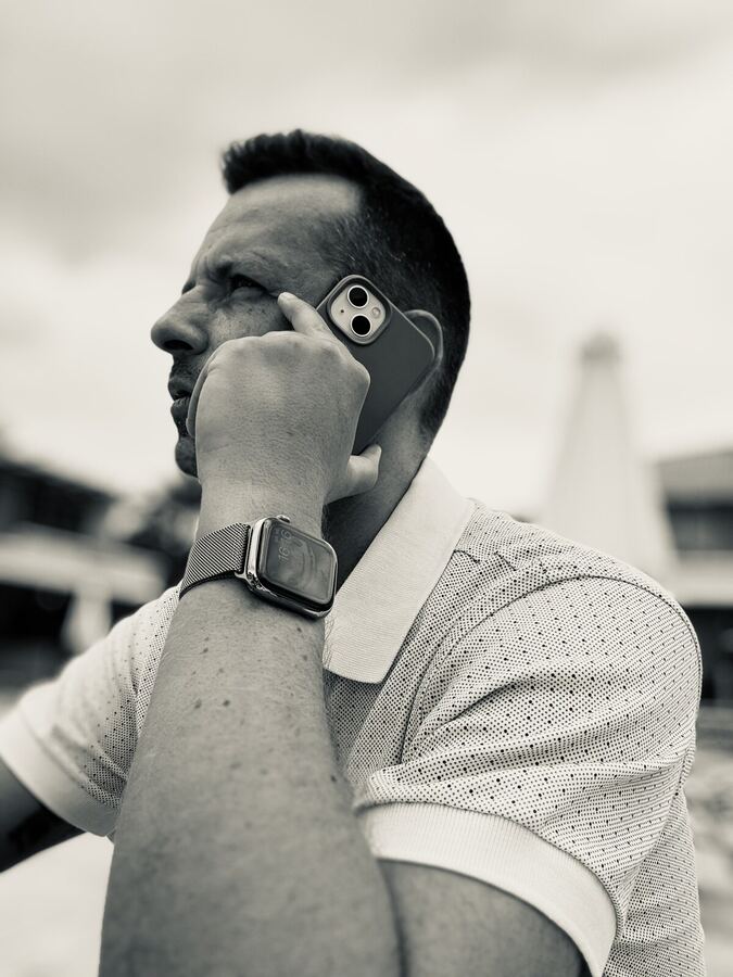 Patrick Helm im Profil telefonierend mit Smartwatch, Schwarz-Weiß-Fotografie