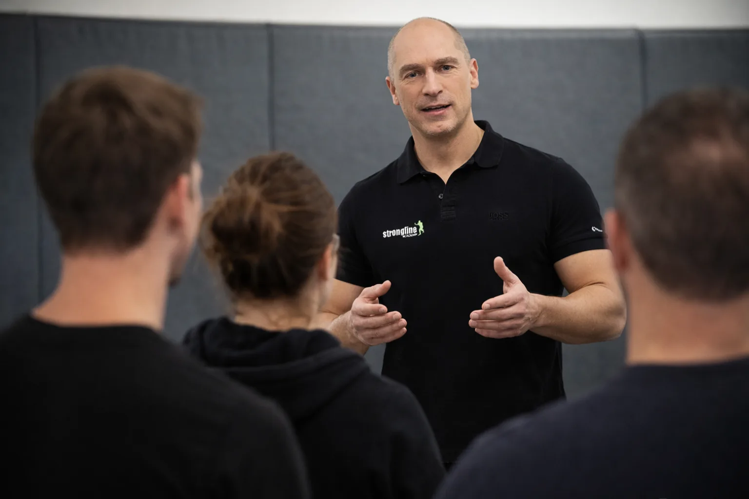 Qualitäts-Trainer demonstriert Selbstverteidigungstechniken vor Gruppe von Kursteilnehmern in Indoor-Studio
