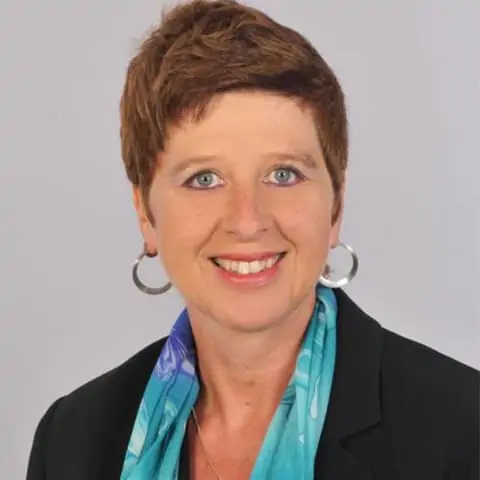 Porträt einer Frau mit kurzen braunen Haaren, Ohrringen und blauem Schal