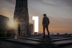 Modul 1: Mann steht auf Dach vor Großstadt bei Sonnenaufgang mit leuchtender Nummer 1