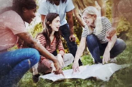 Diverse Gruppe Menschen hockt zusammen und schaut auf Karte oder Rätselblatt